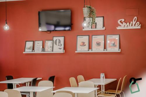 a restaurant with white tables and chairs against a red wall at Hotiday Como Paoli in Como