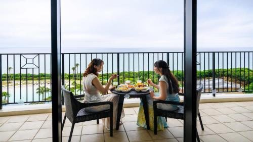 two women sitting at a table eating food on a balcony at Hotel Monterey Okinawa Spa & Resort in Onna