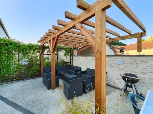 a wooden pergola with blue seating in a backyard at Au Vendangeoir Gîte de groupe piscine in Couvignon