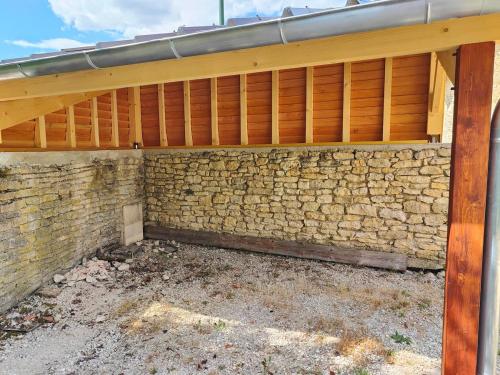 a brick wall with a wooden roof on top at Au Vendangeoir Gîte de groupe piscine in Couvignon