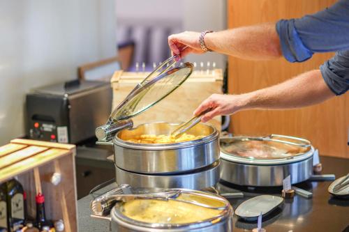 a person cooking food in a pot on a stove at Hotel L'Europe in Colmar