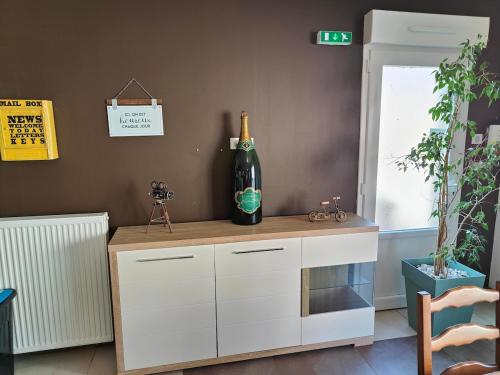 a bottle of wine sitting on top of a cabinet at Au Vendangeoir Gîte de groupe piscine in Couvignon