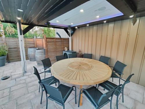 a wooden table and chairs on a patio at Au Vendangeoir Gîte de groupe piscine in Couvignon