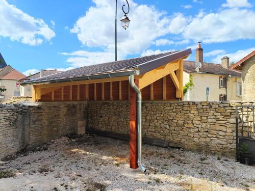a building with a metal roof on a brick wall at Au Vendangeoir Gîte de groupe piscine in Couvignon
