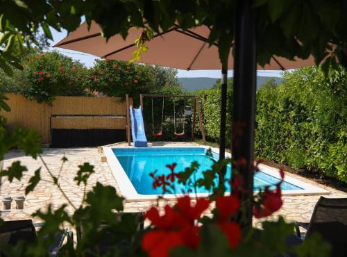 a swimming pool with an umbrella in a yard at Holiday Home Krnić in Šibenik