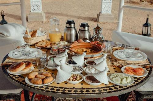 a table topped with plates of food on a table at Merzouga Luxury Dune Camp in Merzouga