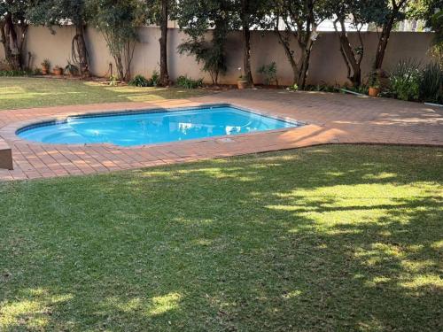 a small swimming pool in a yard with a brick patio at Big 5 Cottage in Pretoria