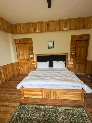 a bedroom with a large bed with white sheets at The Highgrove House, Manali in Haripūr