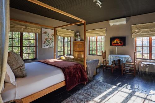 a bedroom with a bed and a fireplace and windows at Boord Guest House in Stellenbosch