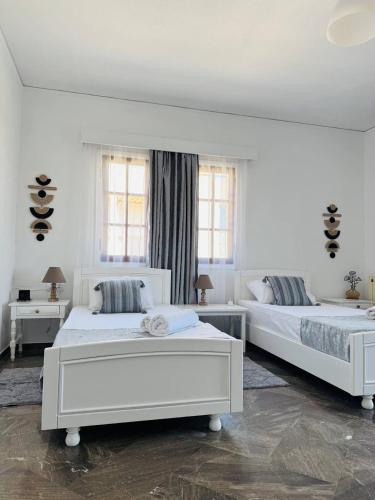 two white beds in a white room with windows at Desire Apartments in Kato Gouves