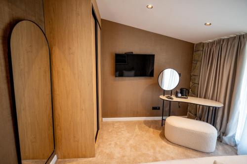 a room with a chair and a table and a television at Hotel Aria in Podgorica