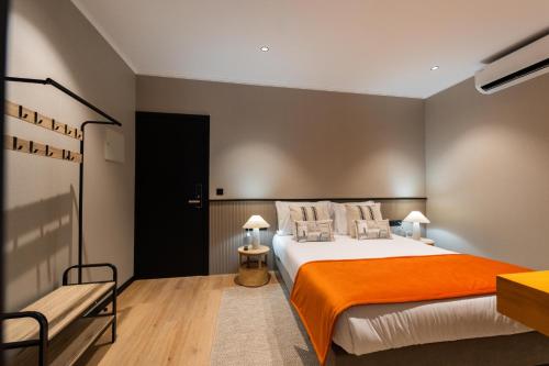 a bedroom with a large bed with an orange blanket at Gaveto de Lisboa - Charming House in Ponta Delgada