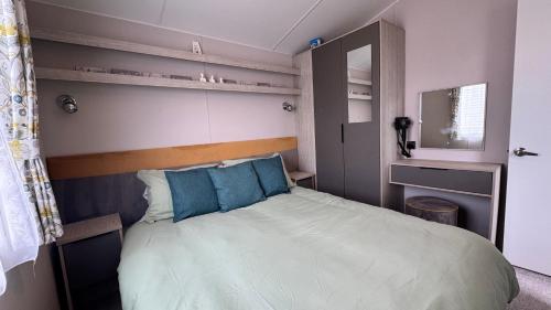 a small bedroom with a bed with blue pillows at Pure Living -West Sands, Quiet Grassy retreat Seal Bay in Selsey