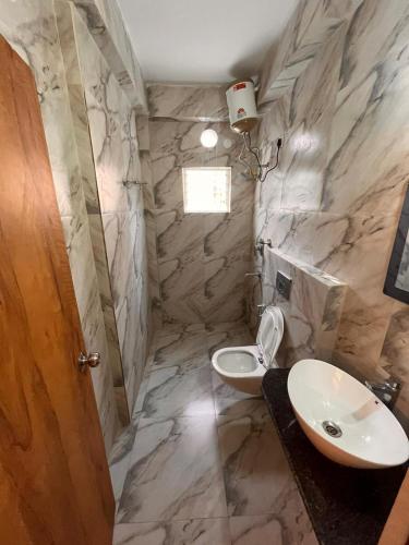 a marble bathroom with a sink and a toilet at Bluestone Residence in Pānchuria