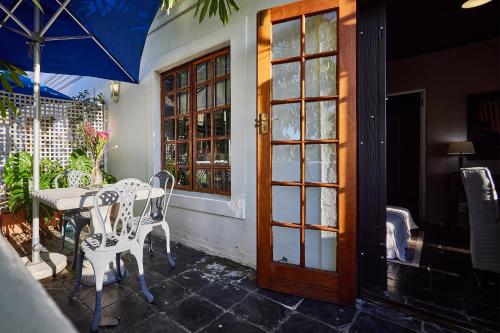 a patio with a table and chairs and a door at Boord Guest House in Stellenbosch