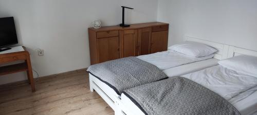a bedroom with two beds and a desk with a television at Willa Na Skarpie in Krynica Morska