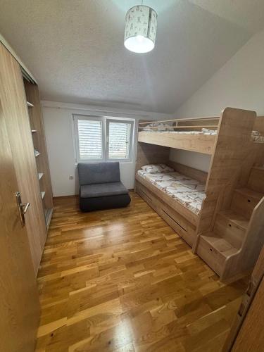 a room with a bunk bed and a chair in it at Cozy Apartment Kuti in Herceg-Novi