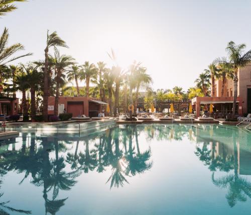 a large swimming pool with palm trees in the background at Pickalbatros Hôtel Du Golf - Adults Friendly 16 Years Plus- All-Inclusive in Marrakech