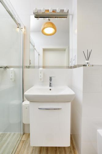 a white bathroom with a sink and a shower at Pokoje Kameralne in Konopnica