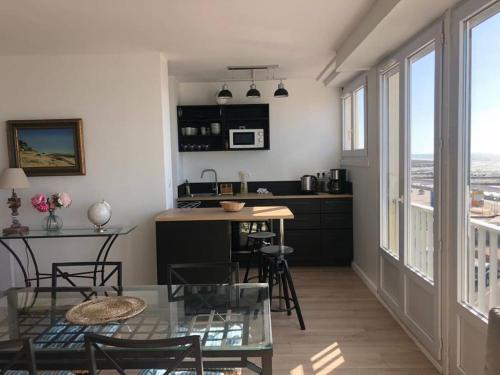 een keuken met een tafel, wat stoelen en een aanrecht bij L'estacade avec sur mer in Le Tréport