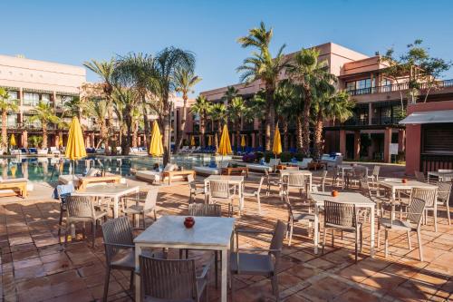a patio with tables and chairs next to a pool at Pickalbatros Hôtel Du Golf - Adults Friendly 16 Years Plus- All-Inclusive in Marrakech