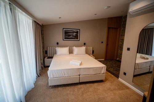 a bedroom with a large white bed and windows at Hotel Aria in Podgorica