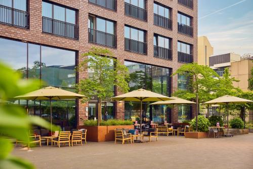 a patio with tables and umbrellas in front of a building at WestCord Hotel Eindhoven in Eindhoven