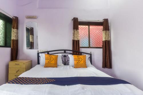 a bedroom with a bed with yellow and blue pillows at Hotel O Muskaan Cottage in Matheran