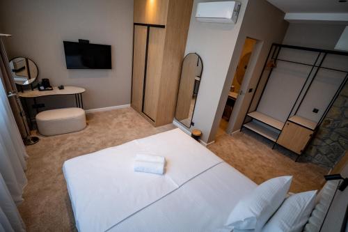 a room with a white bed and a mirror at Hotel Aria in Podgorica