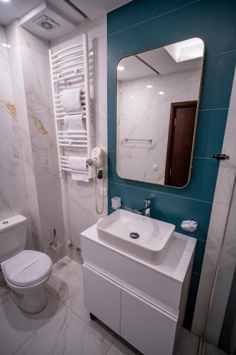 a bathroom with a sink and a toilet and a mirror at Hotel Aria in Podgorica