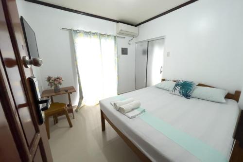 a bedroom with a large white bed and a window at Catappa Lodge Puerto Galera in Puerto Galera