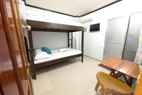 a small room with a bunk bed and a table at Catappa Lodge Puerto Galera in Puerto Galera