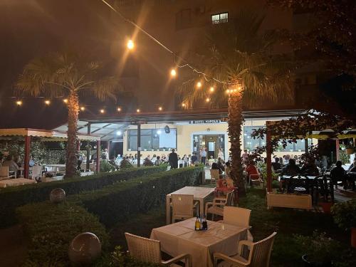 a restaurant with tables and palm trees at night at Hotel Kupola in Spille