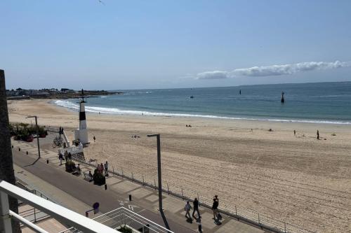 een strand met mensen die over het zand en de oceaan lopen bij Apartment facing the large beach in Quiberon