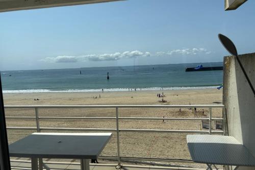 een uitzicht op een strand met een tafel en stoelen bij Apartment facing the large beach in Quiberon
