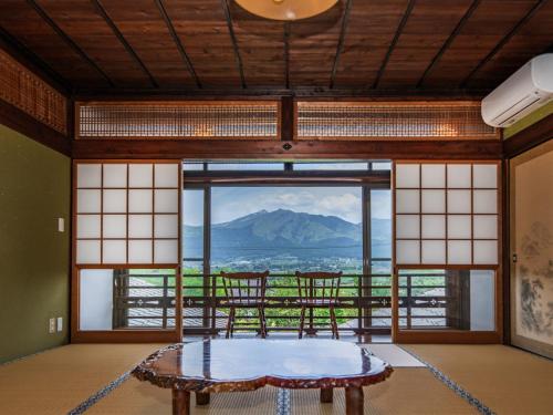 a room with a table in front of a large window at Oyado Denkichi - Vacation STAY 91691v in Minami Aso