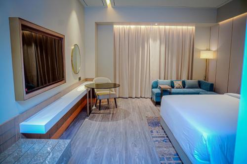 a hotel room with a bed and a table and a couch at Serene Sarovar Premiere Hargeisa in Hargeysa