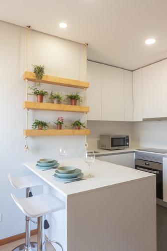 a kitchen with a white counter with plates on it at 3E Apartamento encantador a 3 minutos da praia in Matosinhos