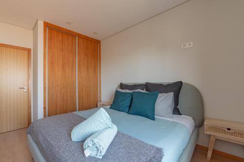 una camera da letto con un letto con cuscini blu e bianchi di 3E Apartamento encantador a 3 minutos da praia a Matosinhos