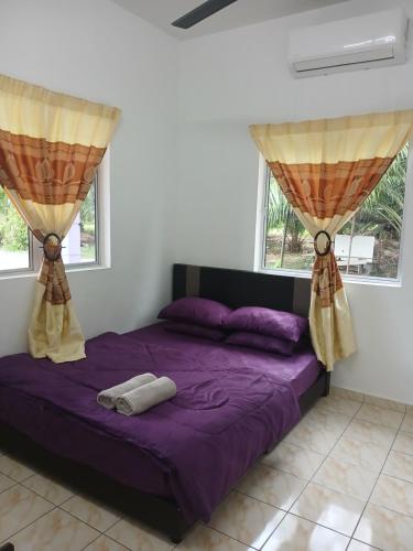 a bedroom with a purple bed and two windows at AA Burger Homestay for Musliim Only in Banting