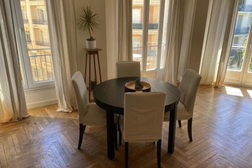 une salle à manger avec une table noire et des chaises blanches dans l'établissement Nice 56m with balcony in rotunda near the sea, à Nice
