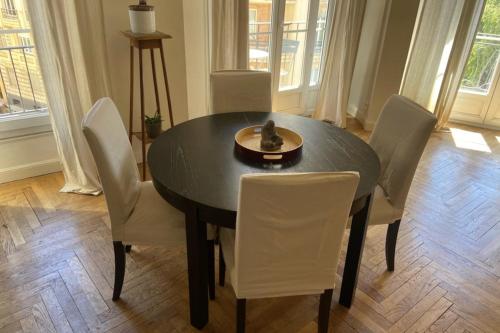 - une table à manger avec des chaises blanches et un bol dans l'établissement Nice 56m with balcony in rotunda near the sea, à Nice