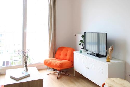 - un salon avec une chaise orange et une télévision dans l'établissement Bright apartment in Saint-Ouen-sur-Seine, à Saint-Ouen