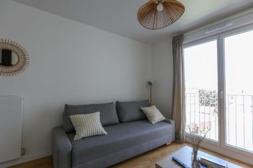 un salon avec un canapé et une grande fenêtre dans l'établissement Bright apartment in Saint-Ouen-sur-Seine, à Saint-Ouen