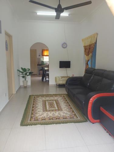 a living room with a black couch and a rug at AA Burger Homestay for Musliim Only in Banting