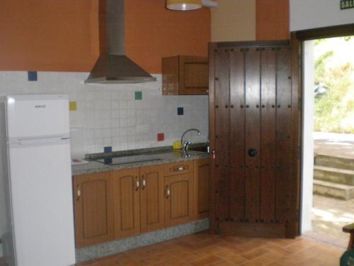 cocina con armarios de madera y nevera blanca en Apartamentos Rurales El Cañuelo de Carcabuey, en Carcabuey