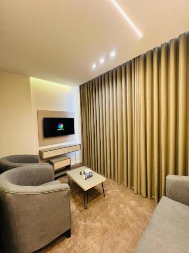 a living room with two chairs and a flat screen tv at فندق الأمراء بلازا in Ma‘ān