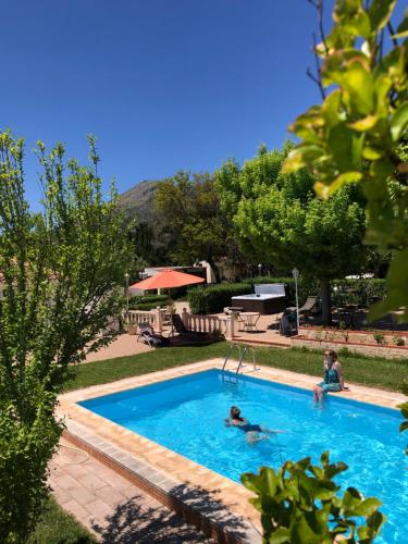 a swimming pool with two people in the water at Casa Rural Y Spa de Regina in Turballos