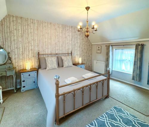 a bedroom with a large bed and a chandelier at The Old Shop at Savile House - Sherwood Forest in Ollerton