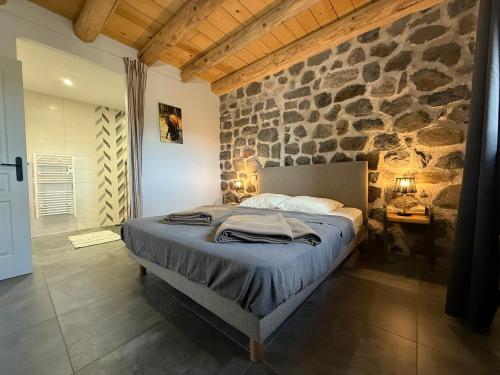 un lit dans une chambre avec un mur en pierre dans l'établissement Gîte LE RABIOUZE - 4 épis, 15 pers, 22 couchages - Ancienne Bergerie rénovée, cachet d'origine conservé - Vue magnifique - Label Ecogîte, à Arlempdes